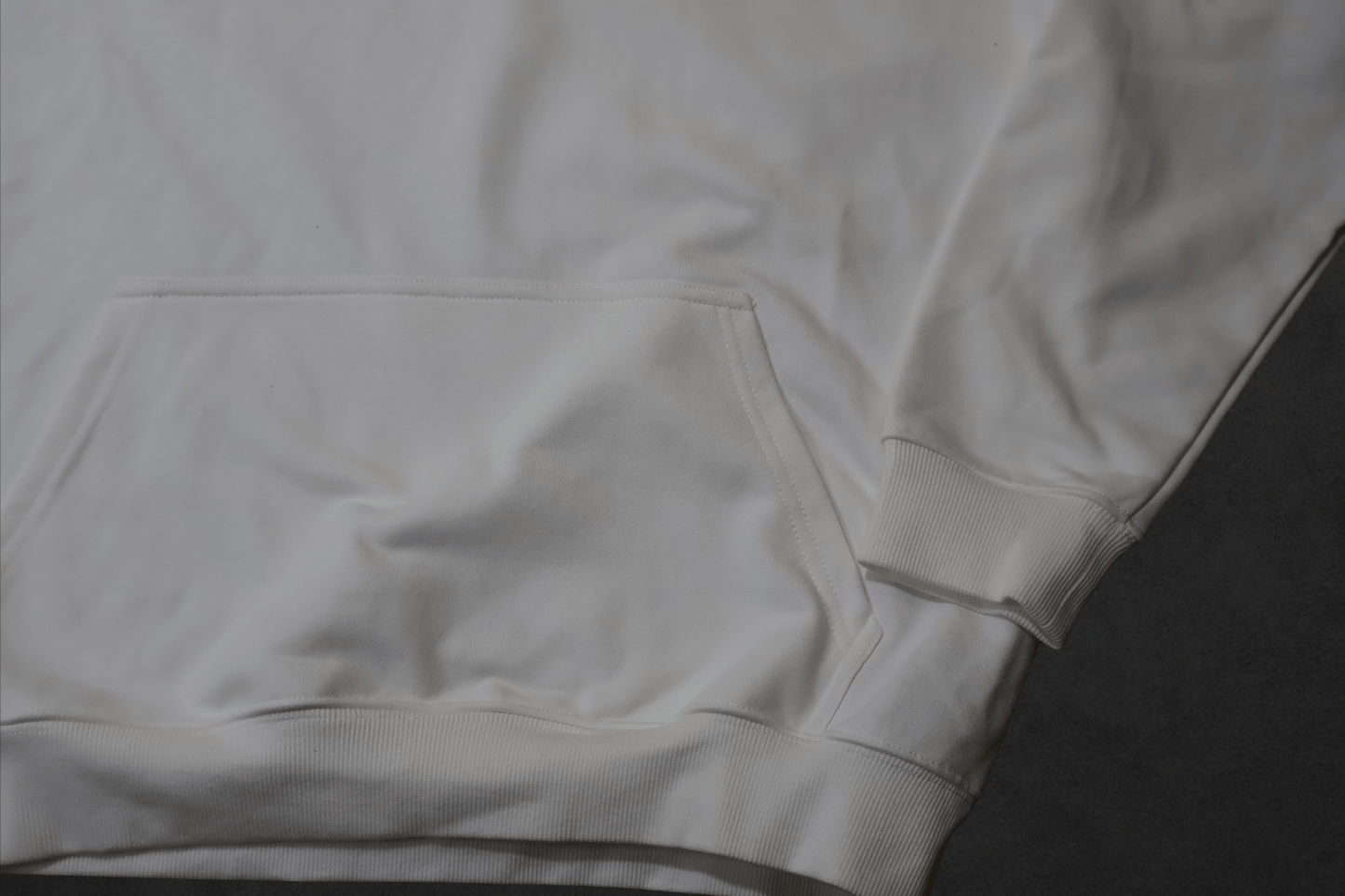 Close-up of the SR Black & White Premium Hoodie 450g - Unisex showing the pocket and cuff details in soft white fabric.